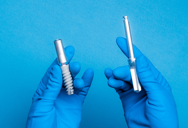 Blue-gloved hands holding precision-machined medical components