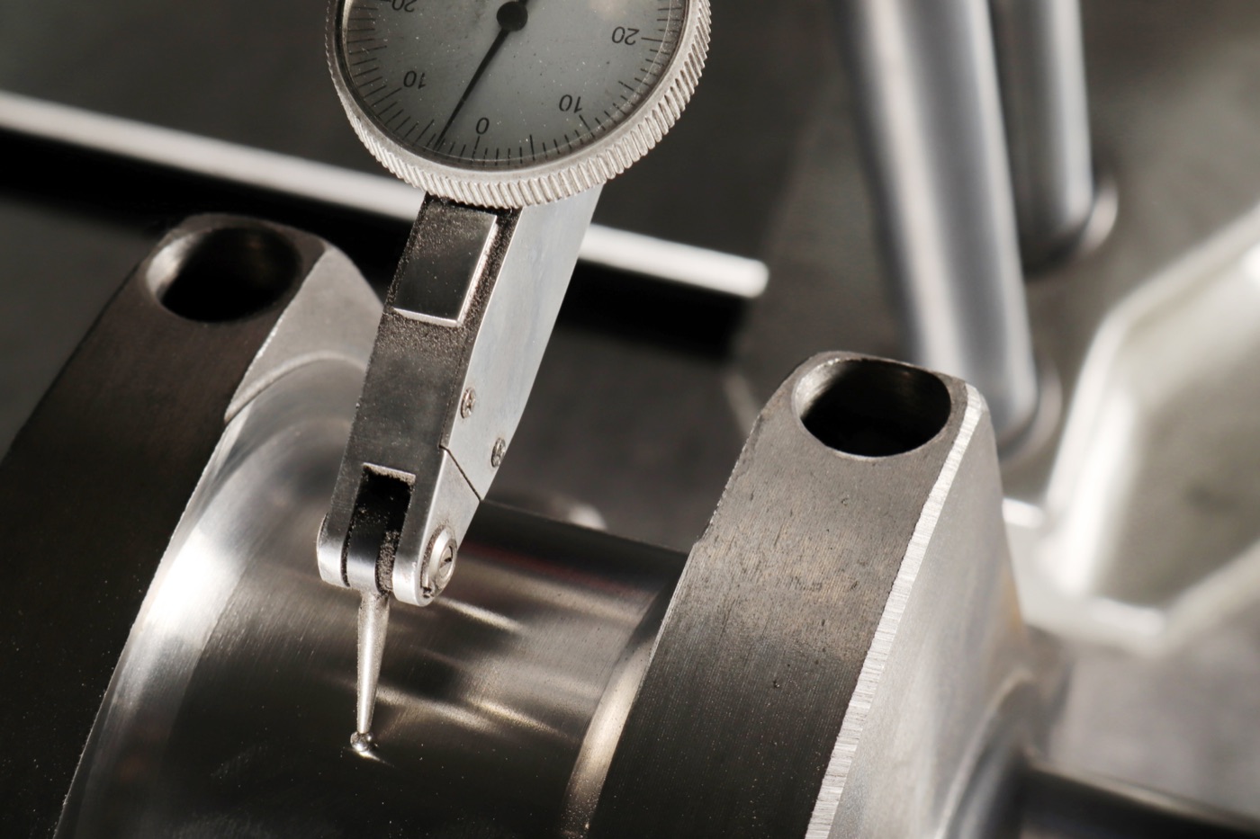 Dial indicator measuring a machined metal component during inspection